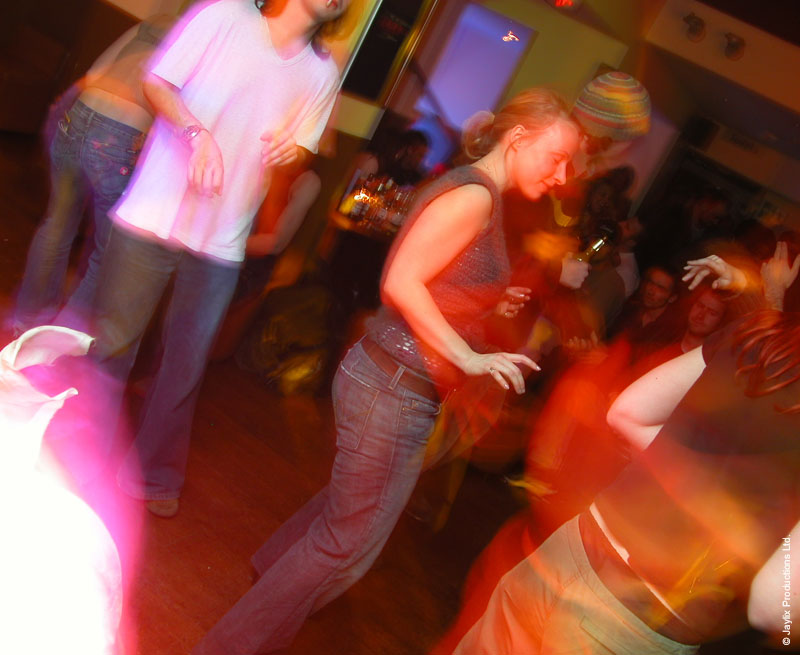 Blurred dancers in motion on a dance floor lit by orange and pink light