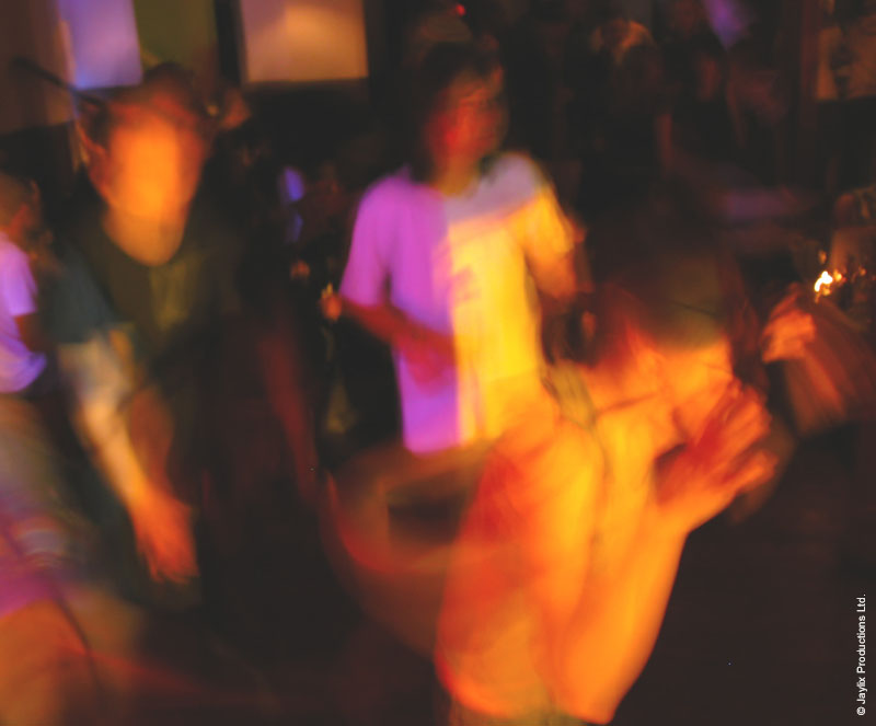 Blurred dancers in purple and orange light on a dark dance floor