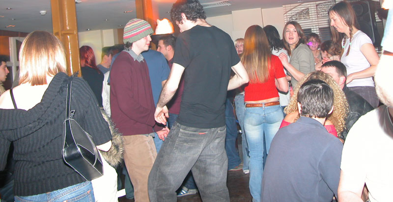 A crowd of people dancing close together in a bar