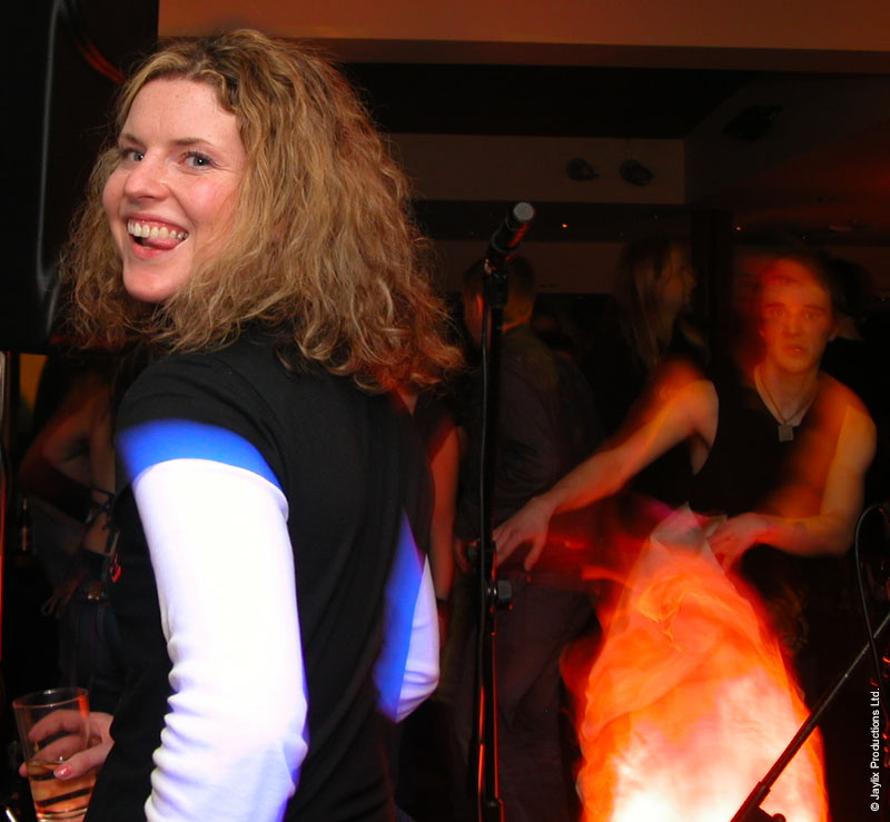 A smiling woman with curly hair in a black and white top looks back at the camera, with an orange glow behind