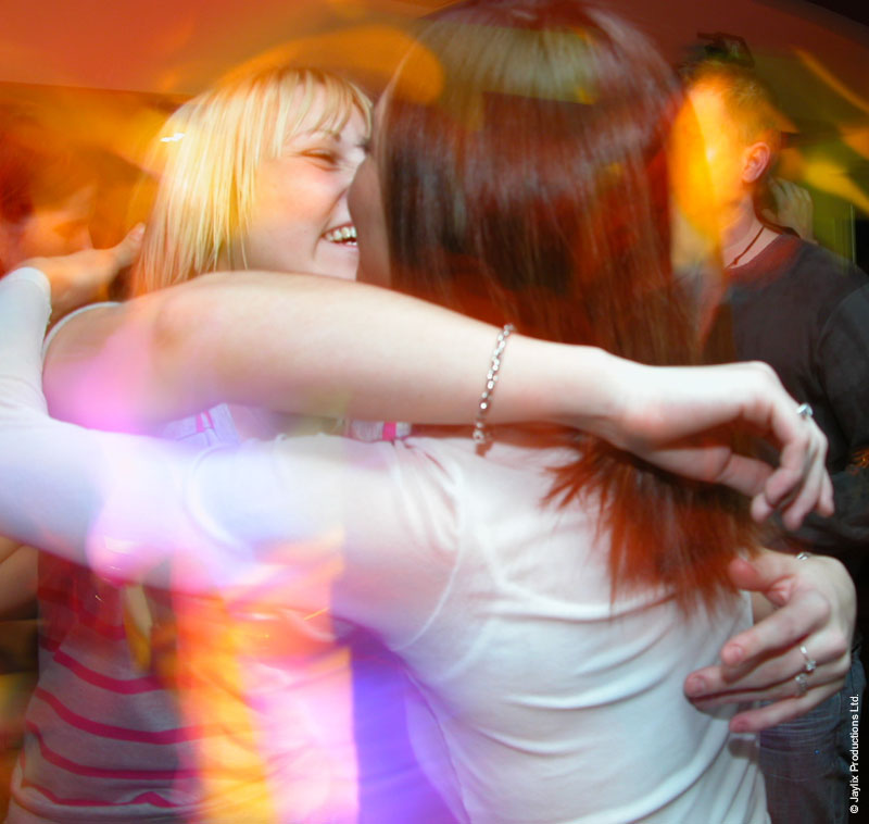 Two people hug and laugh in a blur of pink and orange light
