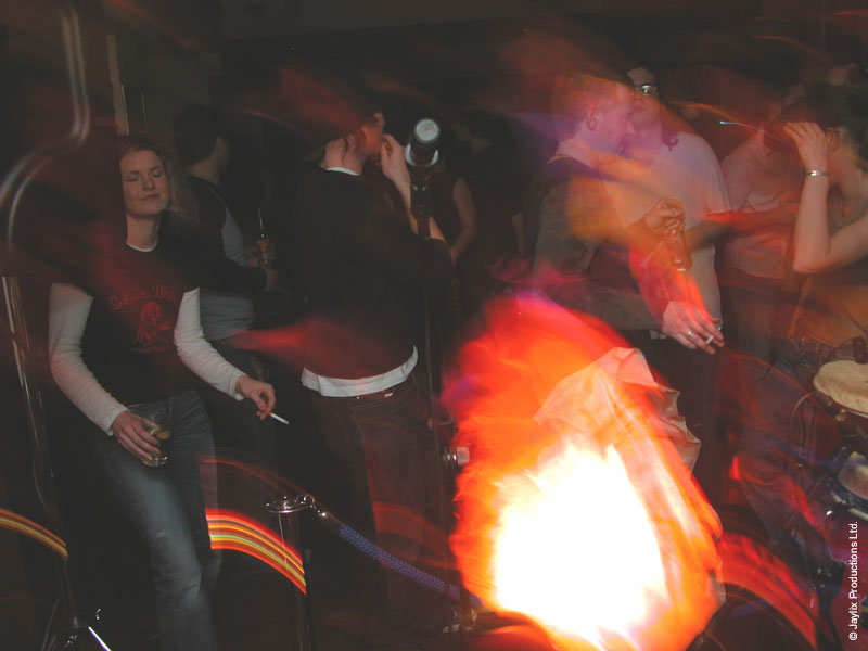 Blurred people in a dark bar with a bright orange glow in the foreground