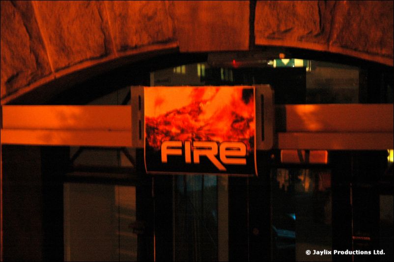 An illuminated FIRE sign beneath a stone archway at night