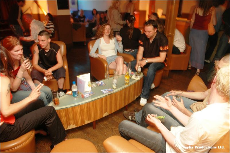 People sit around a low table in a bar lounge, with leather armchairs and drinks