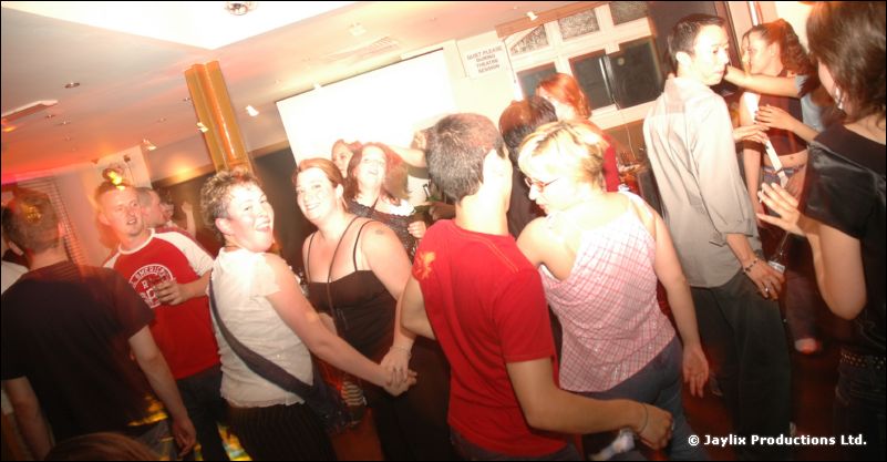 People dancing in a busy bar, seen from behind