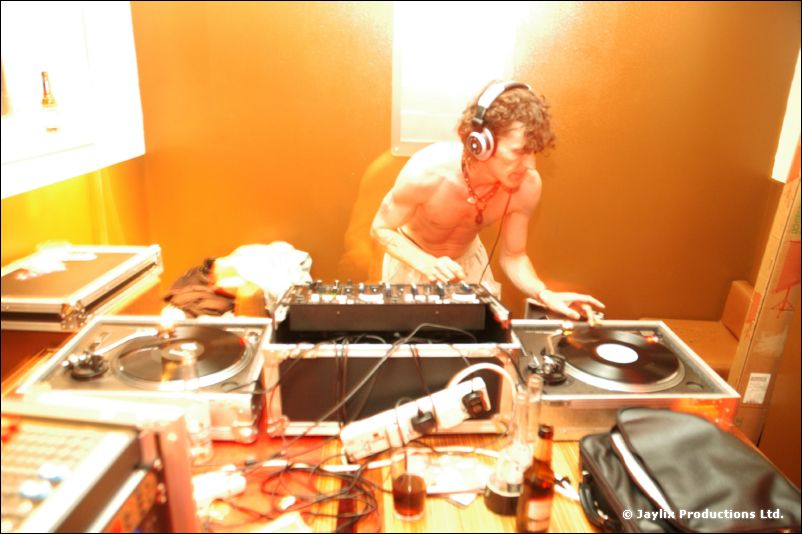 A person in headphones plays records at DJ decks in a warmly lit room