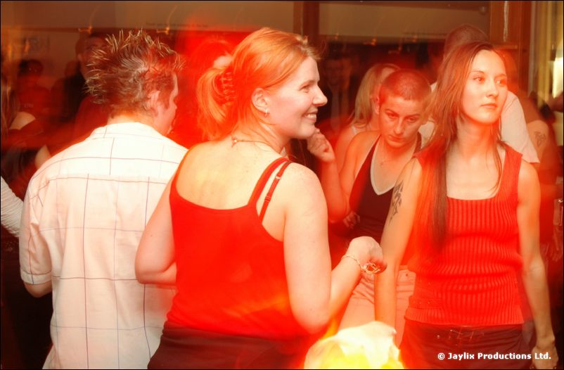 Two women in red tops and two other people in a packed, red-lit bar