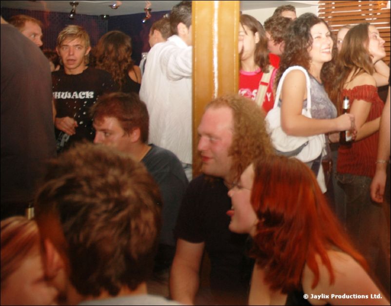 Crowded people in a bar, several turned towards the stage