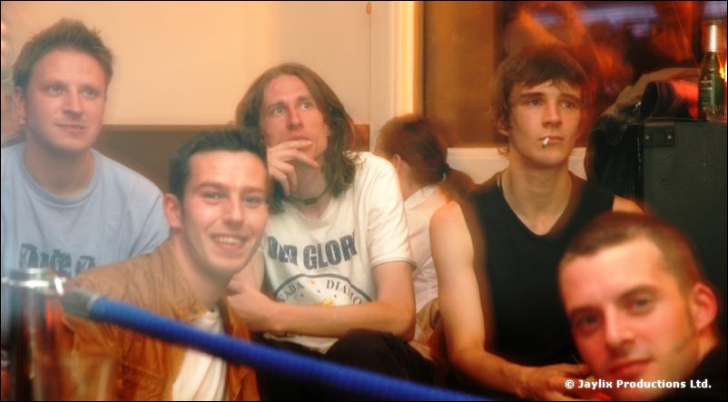 Five people look at the camera on a sofa, one with a cigarette