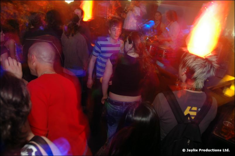 People dance in a crowded club with an orange flame effect glowing above
