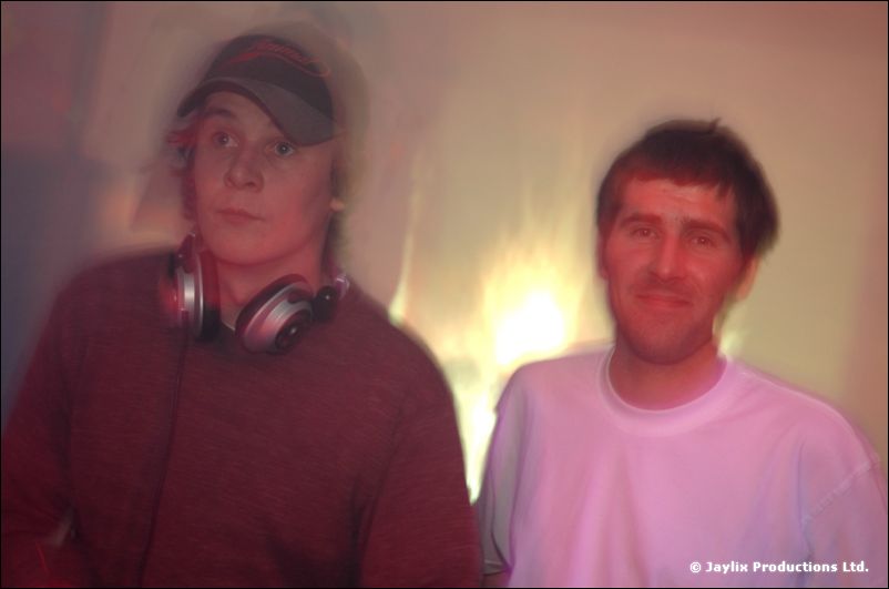 Two men pose, one in a cap with headphones round his neck, the other in a white T-shirt