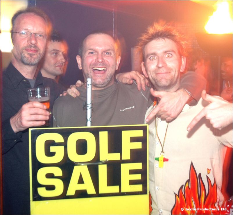 Three men hold a Golf Sale sign and pose, one holding a pint and one pointing at the camera