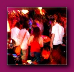 Small framed thumbnail of a packed dance floor in red light with people in white tops