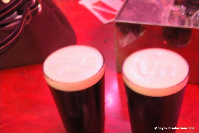 Two pints of stout on a red table