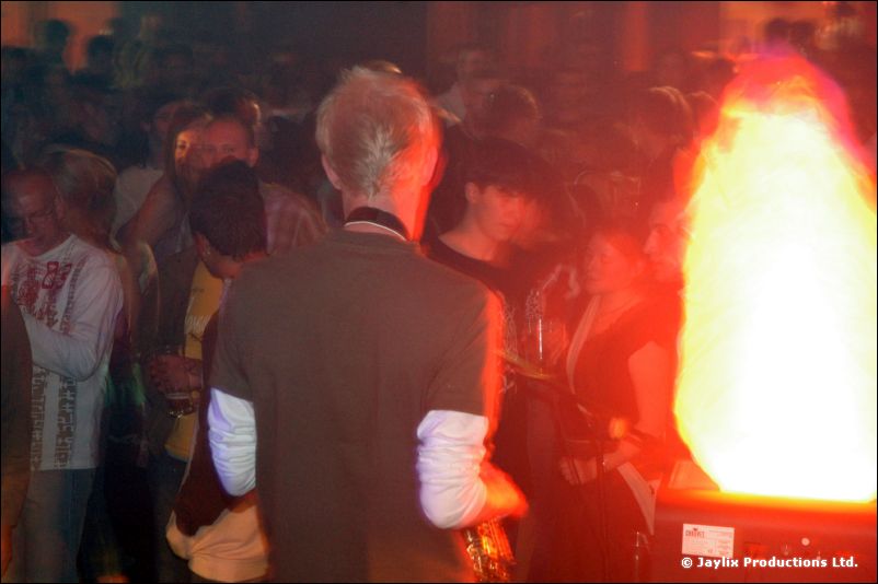A person in a grey jacket stands with their back to the camera beside a glowing flame effect
