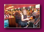 Small thumbnail of a person sitting at a bar with bottles and lights behind