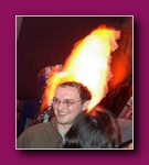 Small thumbnail of a smiling person with glasses with a flame blurred above their head