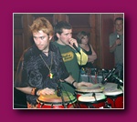 Small thumbnail of a person with spiky hair playing congas, another person behind