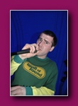 Small thumbnail of a person in a green top speaking into a microphone against a blue backdrop