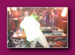 Small thumbnail of a DJ in a pale top at the decks in front of a crowd