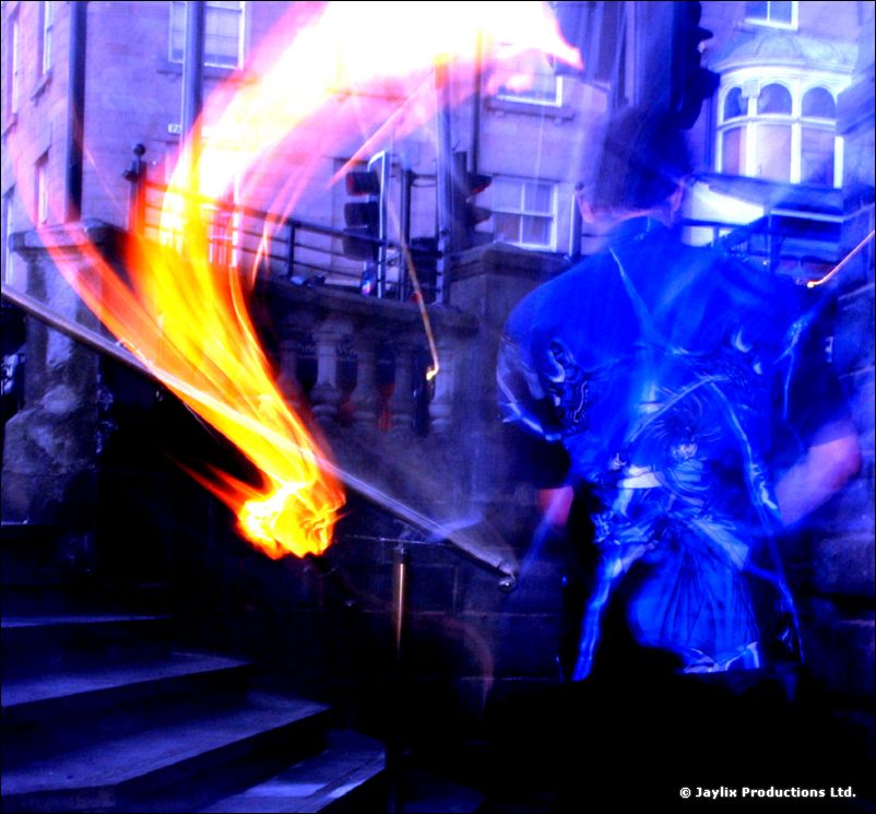 A blurred person in blue with a blazing fire trail on stone steps