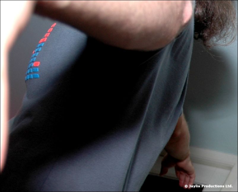 Close view of a person's torso in a grey t-shirt with a small red and blue print