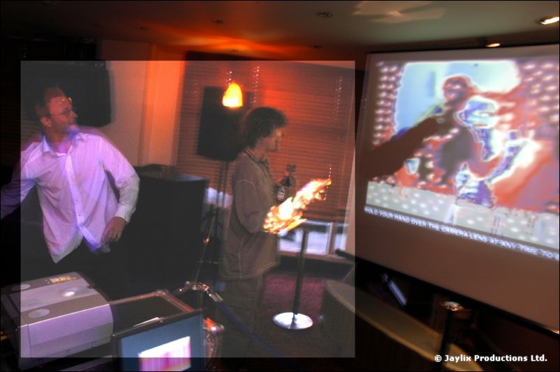 A person in a white shirt and another holding a microphone stand a room with a projector screen