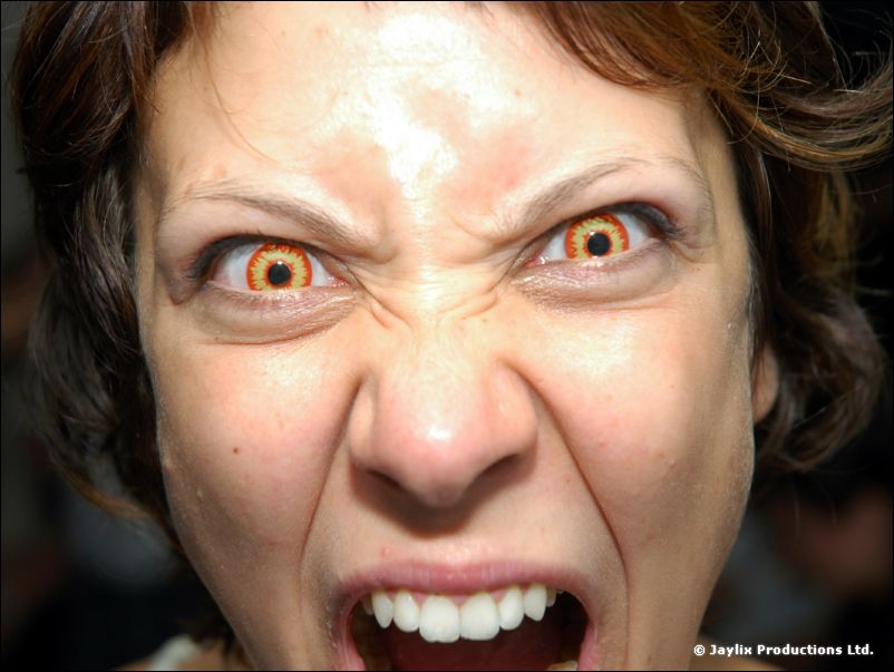 Close-up of a person with orange contact lenses snarling at the camera