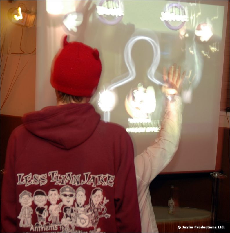 A person in a red hat and hoodie reading Less Than Jake faces a projected image