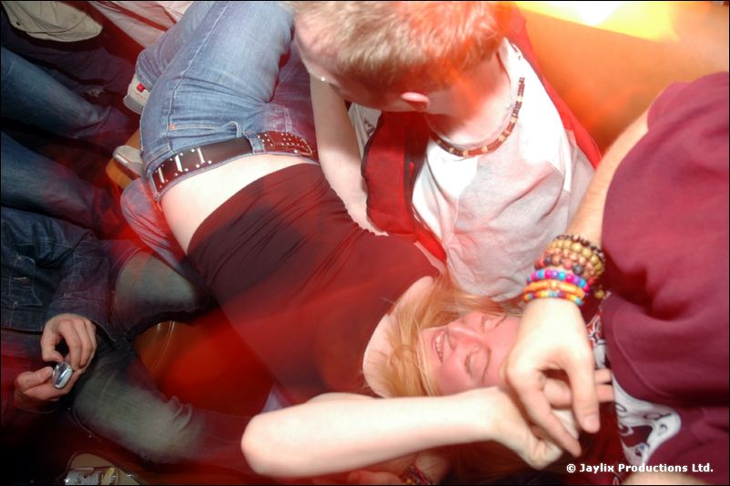 Blurred view of people lying and leaning together on a sofa in red light