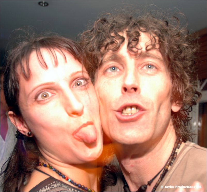 Two people pressed cheek to cheek, one sticking out a tongue, the other pulling a face