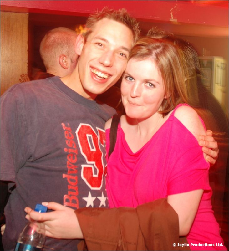 A smiling man in a Budweiser t-shirt and a woman in a pink top posing close together