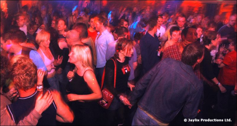 A dense crowd of dancing people under blue and red lights