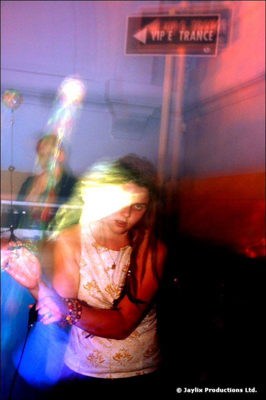 A blurred dancer in a white top in front of a sign reading "VIP E TRANCE"