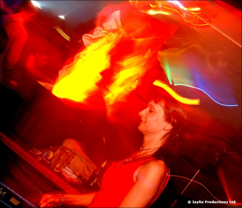 A blurred long exposure of a person in red with streaks of orange and yellow light