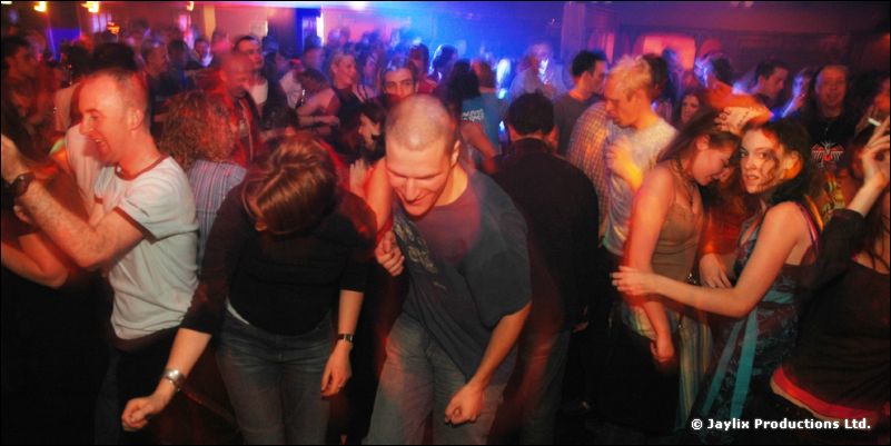 A crowd of people dancing in a dark room under blue light