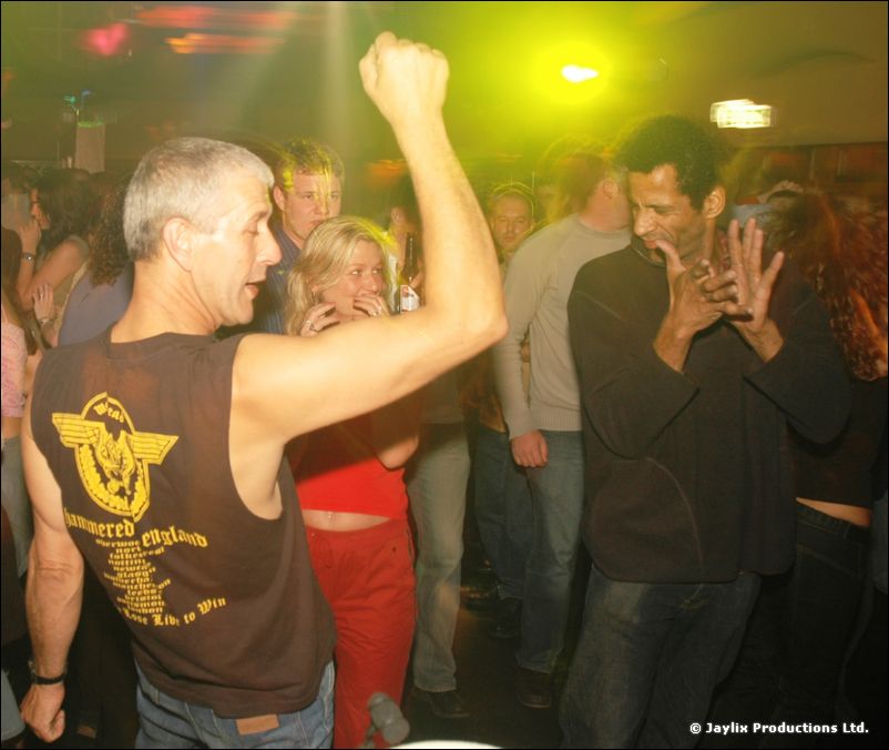 A man in a sleeveless top with a raised fist dances in a crowd