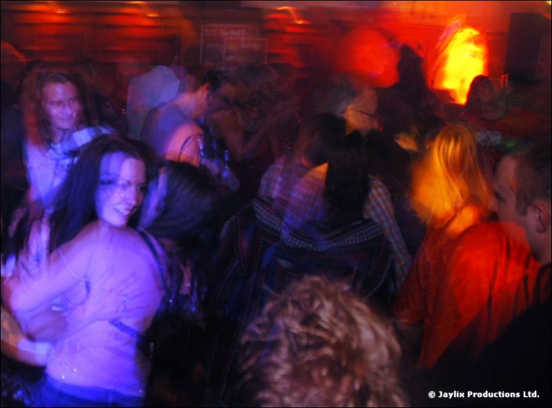 A blurred crowd of dancing people in red and blue light