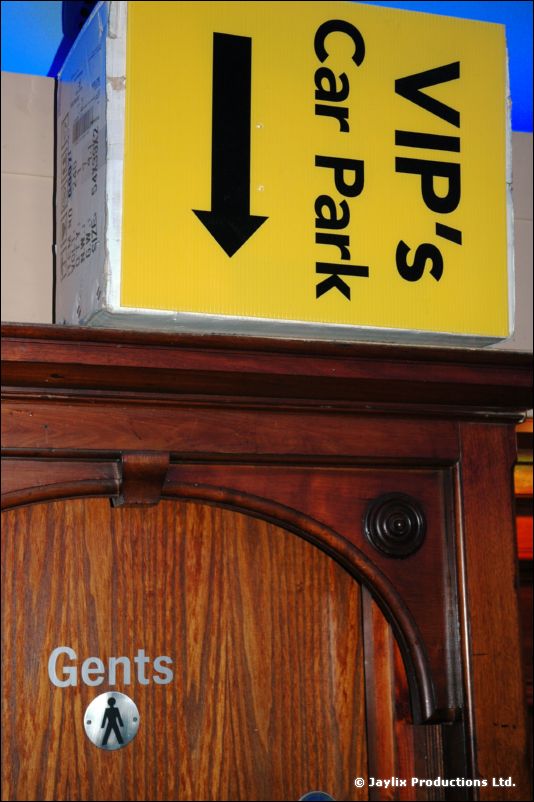 A yellow sign reading "VIP's Car Park" with a down arrow, above a door marked "Gents"