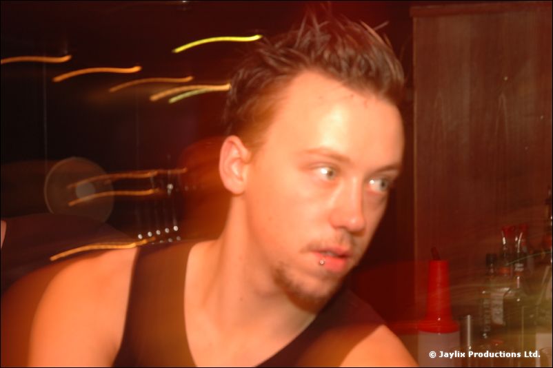 Close-up of a person in a dark vest glancing sideways, with light streaks behind