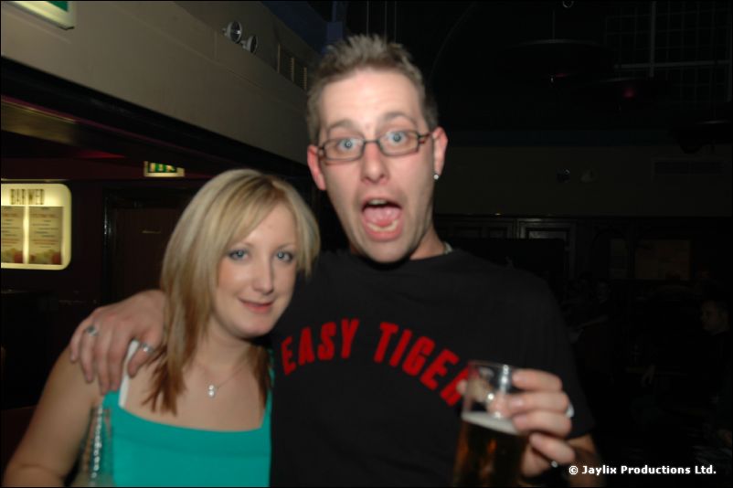 A woman in a turquoise top and a man with glasses in an "Easy Tiger" t-shirt pose together