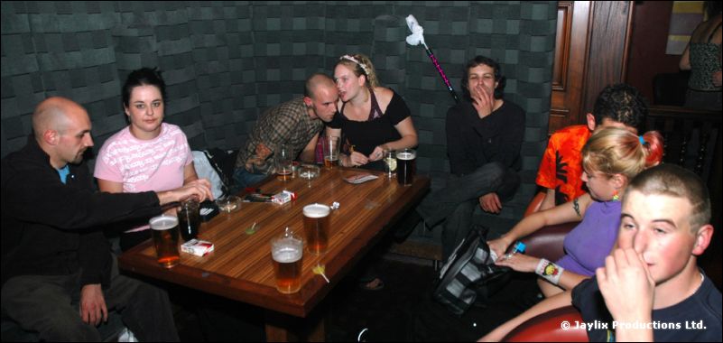 People sit around a wooden table with drinks in a bar with grey padded walls