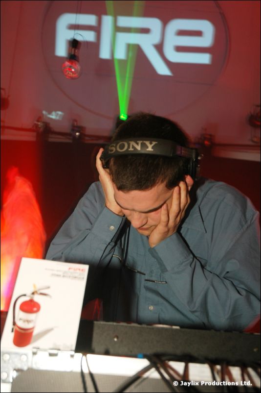 A DJ in Sony headphones rests his head in his hands, under a projected "FIRE" logo