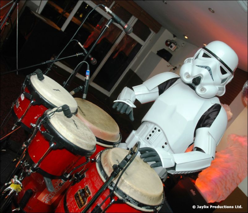 A person in a stormtrooper costume plays conga drums
