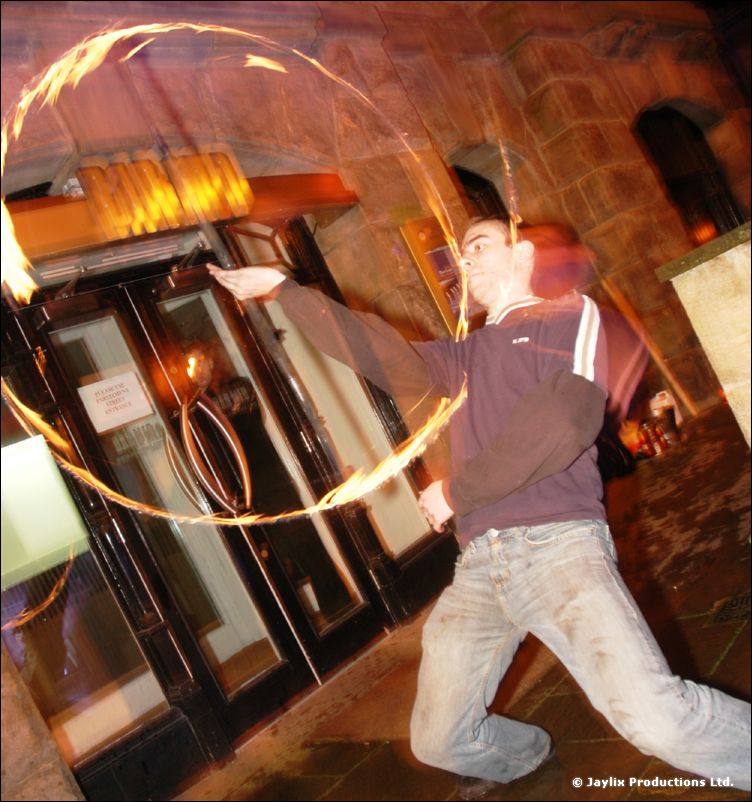 A person in a purple top leans back while spinning a ring of fire outside a doorway