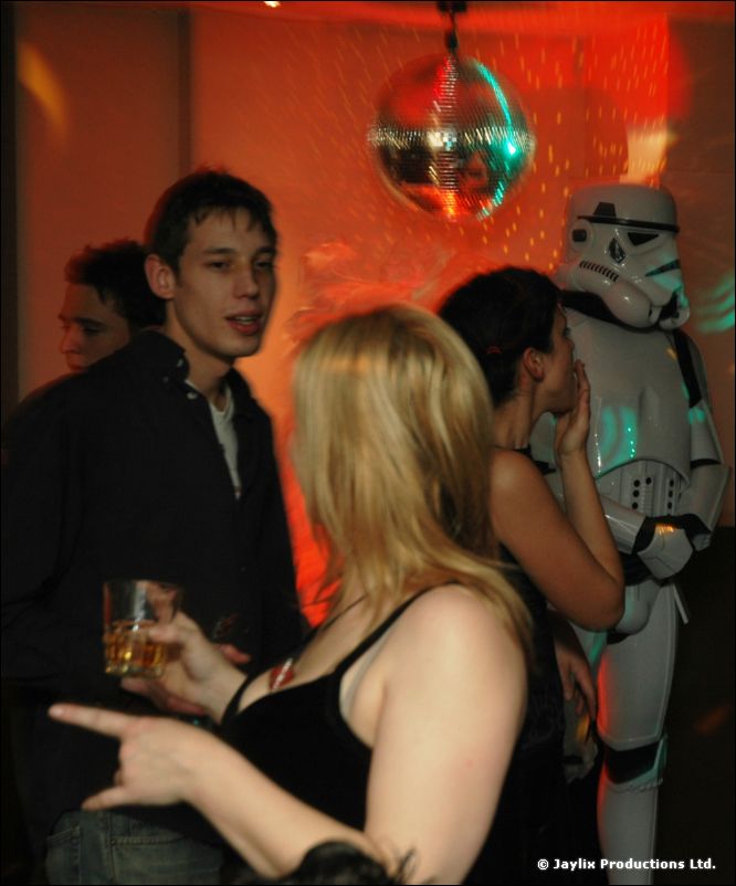 People chat in front of a mirror ball, with a stormtrooper costume standing behind them