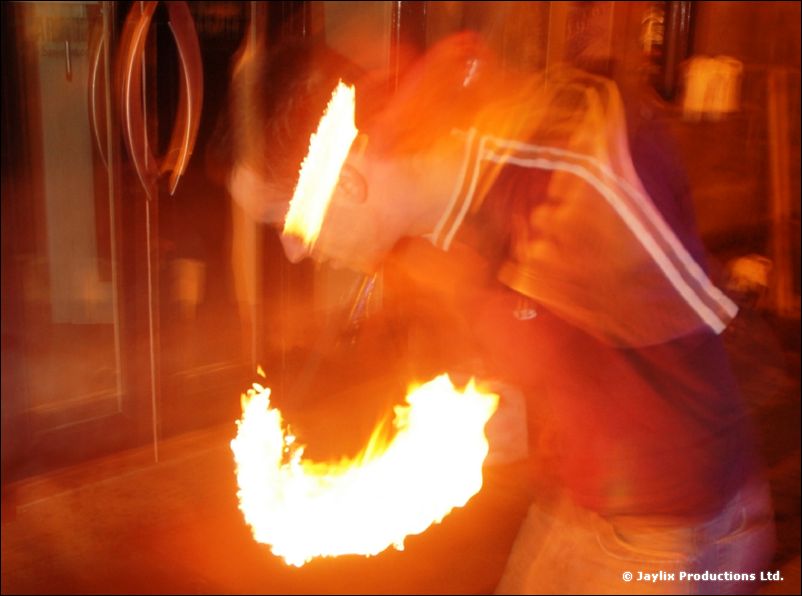 Blurred fire trails and a person in a striped jacket, seen close up at night