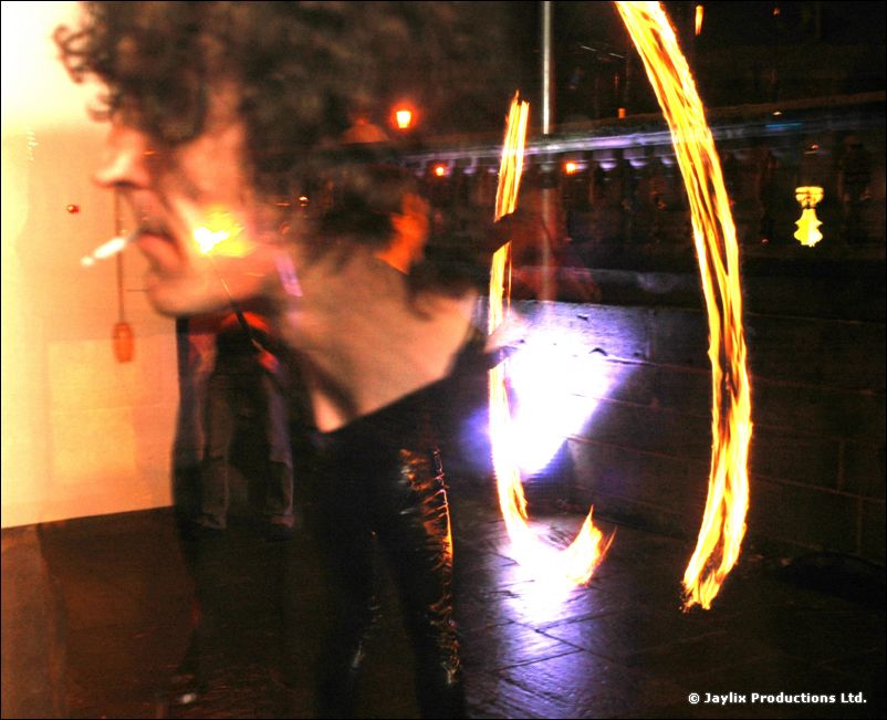 A blurred profile of a curly-haired person beside fire trails at night