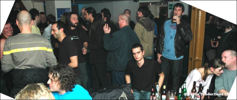 A crowd of people standing and sitting in a busy bar, with bottles at the front