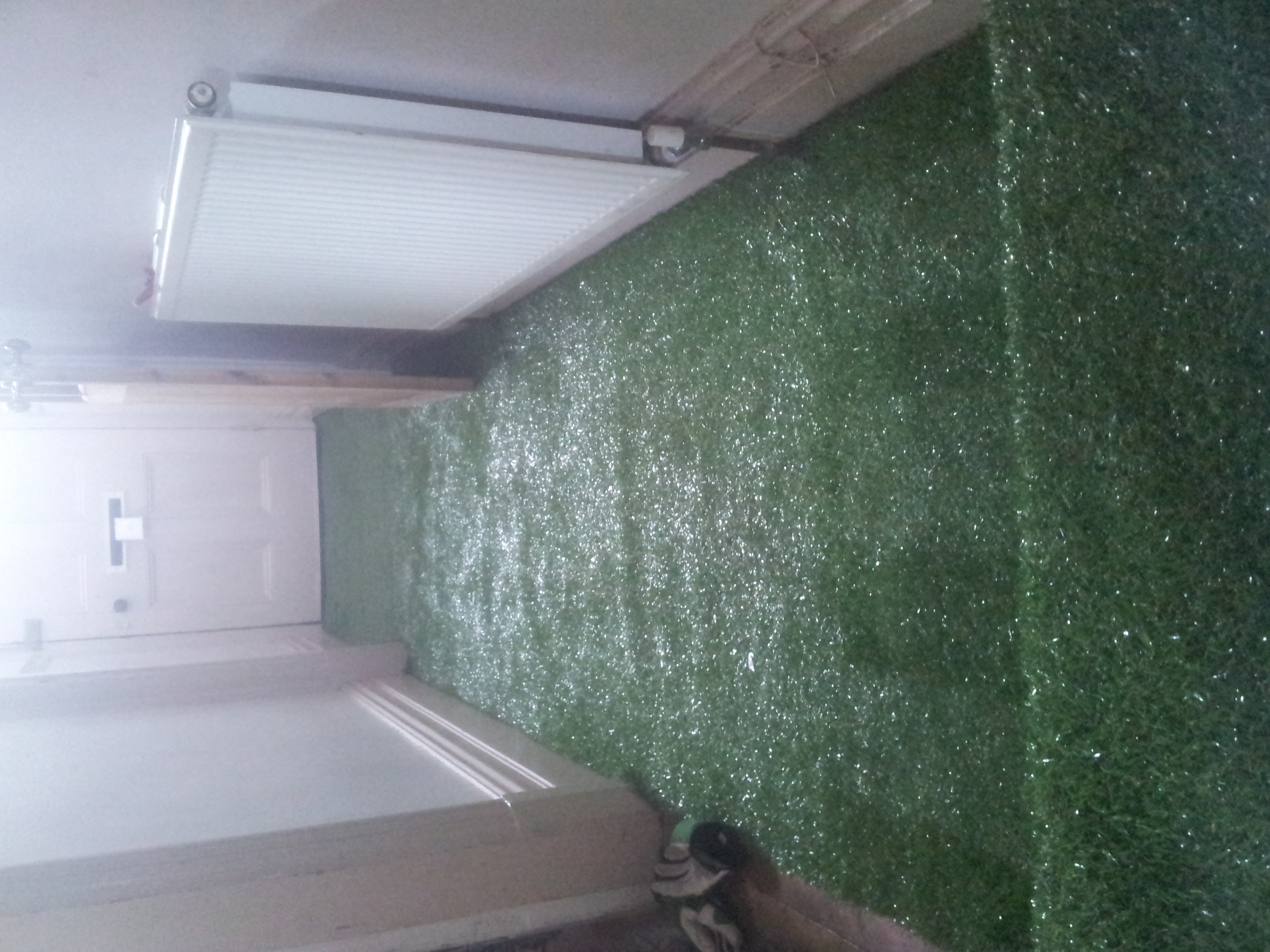 A sideways photo of a hallway floor covered in artificial turf